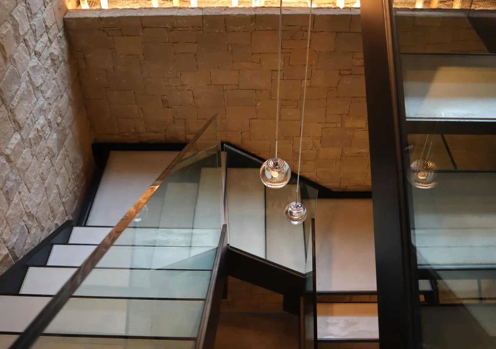 Escalera interior de piedra y cristal en un edificio de Edificaciones Moreno